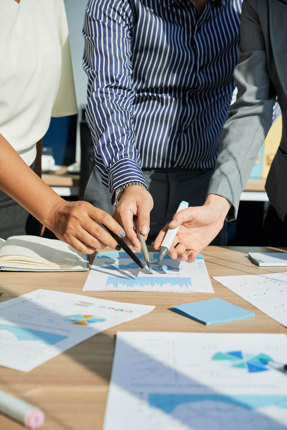 Three people looking at charts on a paper.
